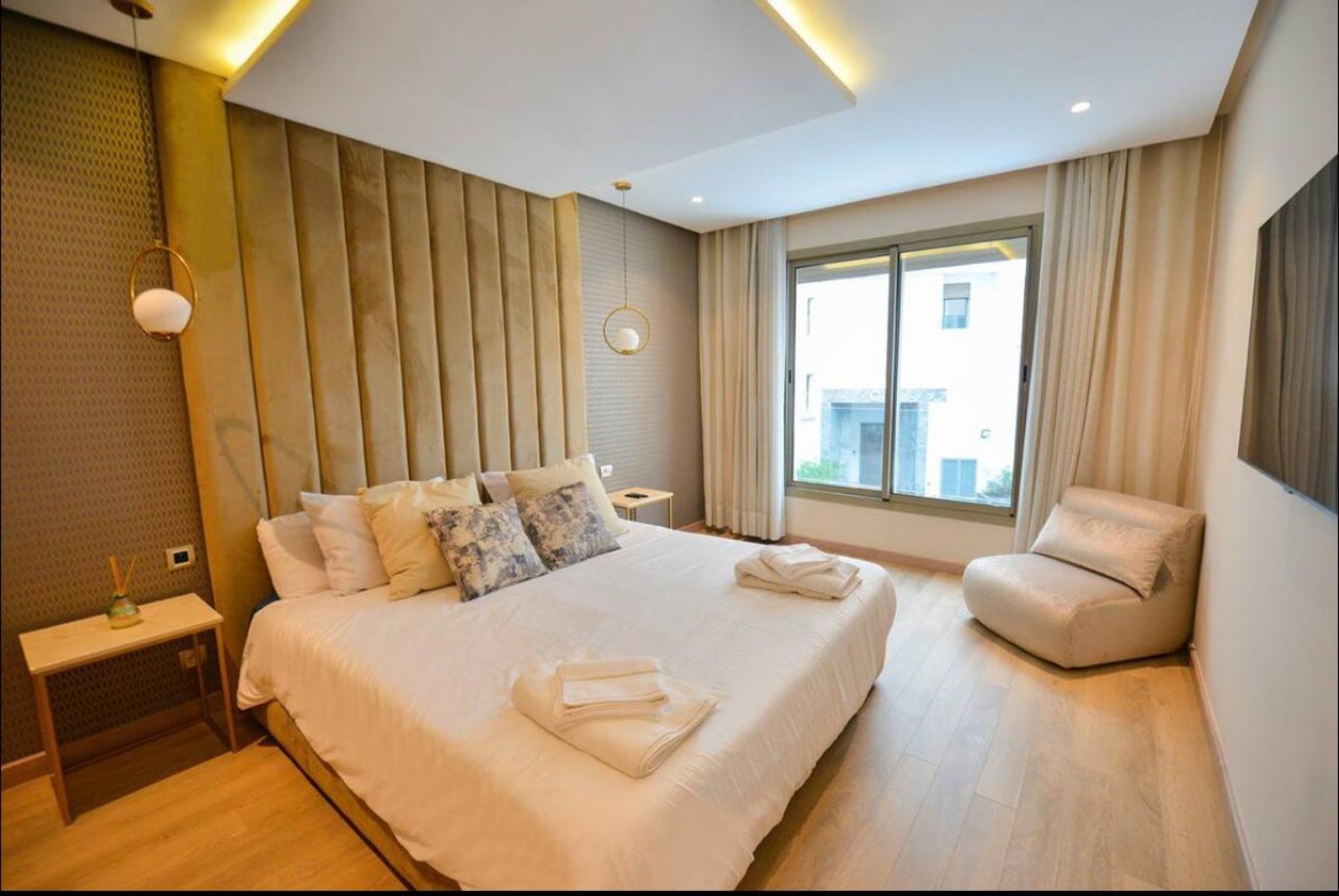 Chambre avec lit double, tête de lit dorée et fauteuil